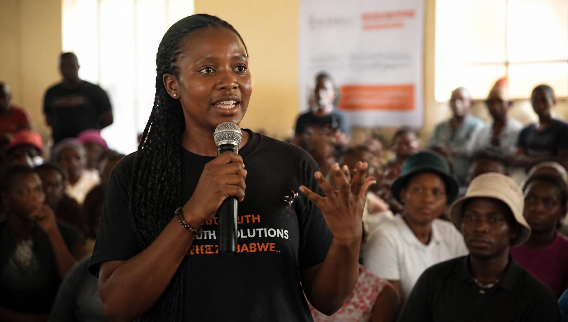 Young African advocate speaking to a community audience with a microphone