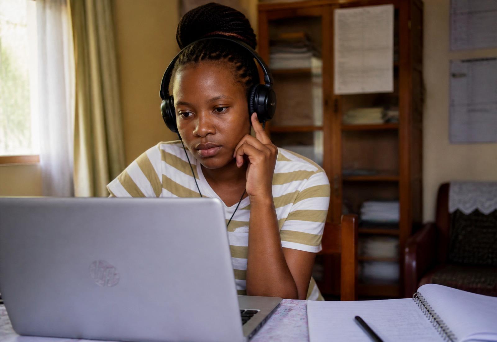 Young African woman attentively participating in an online event on her laptop